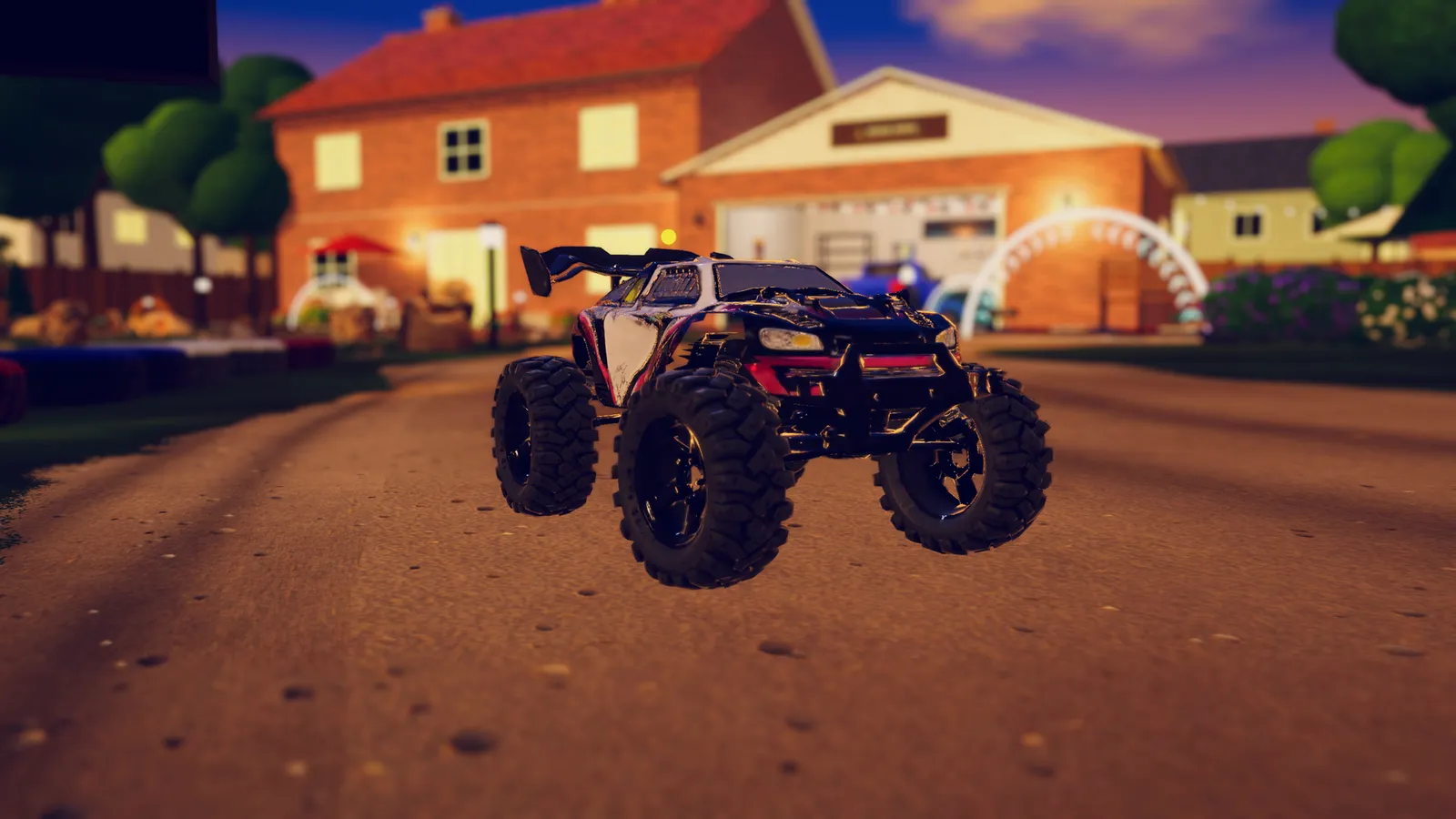 A black, white and pink toy monster truck with huge tyres on a dirt road at dusk, in front of a brick house and garage.